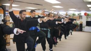 Adults Doing A Kung Fu Stunt In A Kung Fu School For Self Defense/MMA/Self-defense Near You With Swords as Weapons